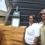 BRIDGE Inset Ms Sowah third from right handing over the streetlight polythank and one of the footbri
