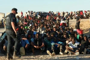 Migrants and asylum seekers wait in line to receive food and drink from the Red Cross in Ceut Spain